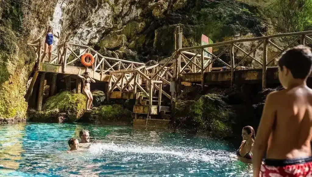 Visitors exploring a natural cenote surrounded by lush greenery at Scape Park in Punta Cana.

